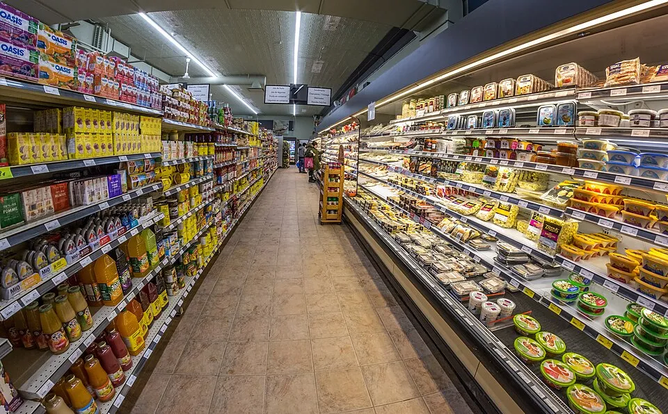 Pasillo central de un supermercado con las estanterías llenas y la iluminación encendida