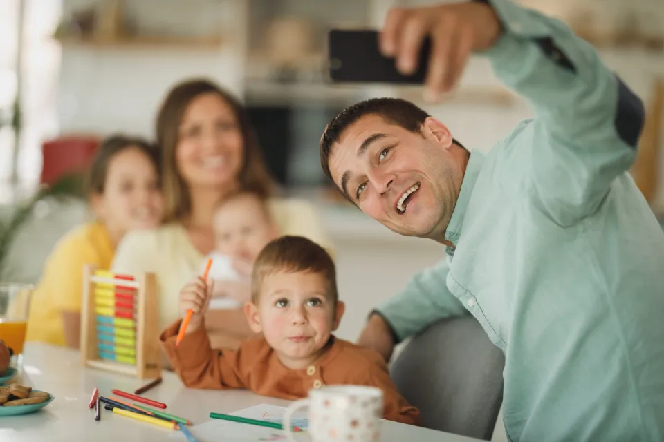 Padre haciendo una foto con el móvil a la familia mientras desayunan juntos